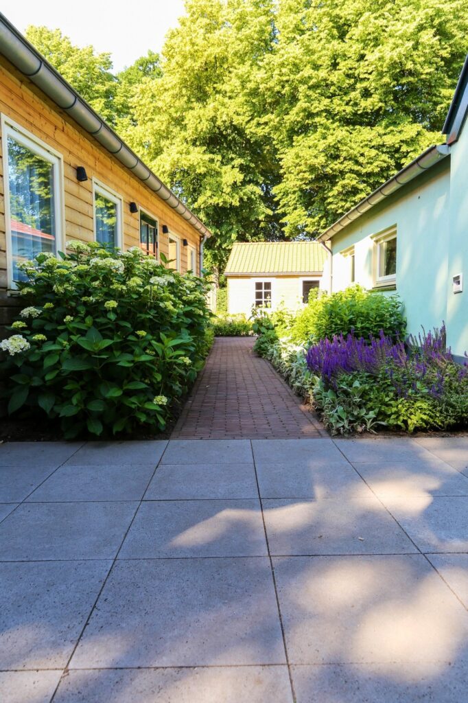 Tegelpad tussen tuinhuisjes met borders