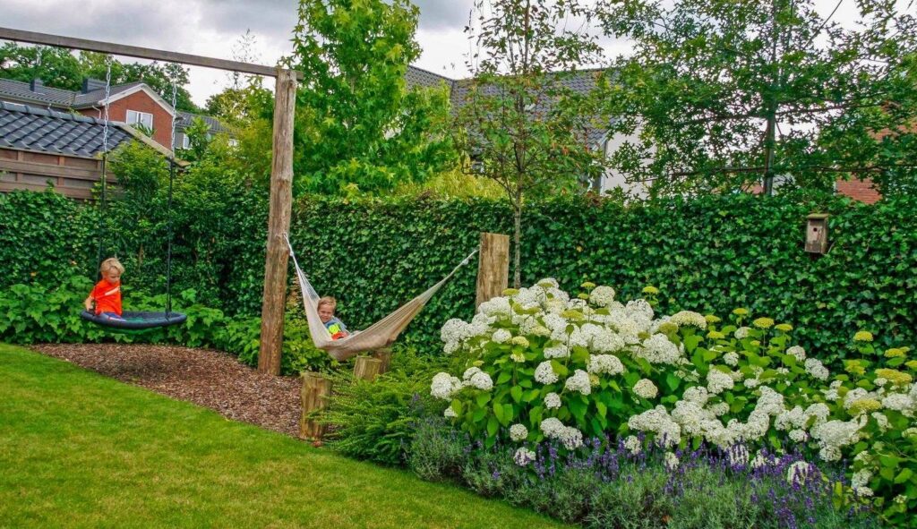 Kindvriendelijke tuin met hangmat, schommel en witte hortensia's