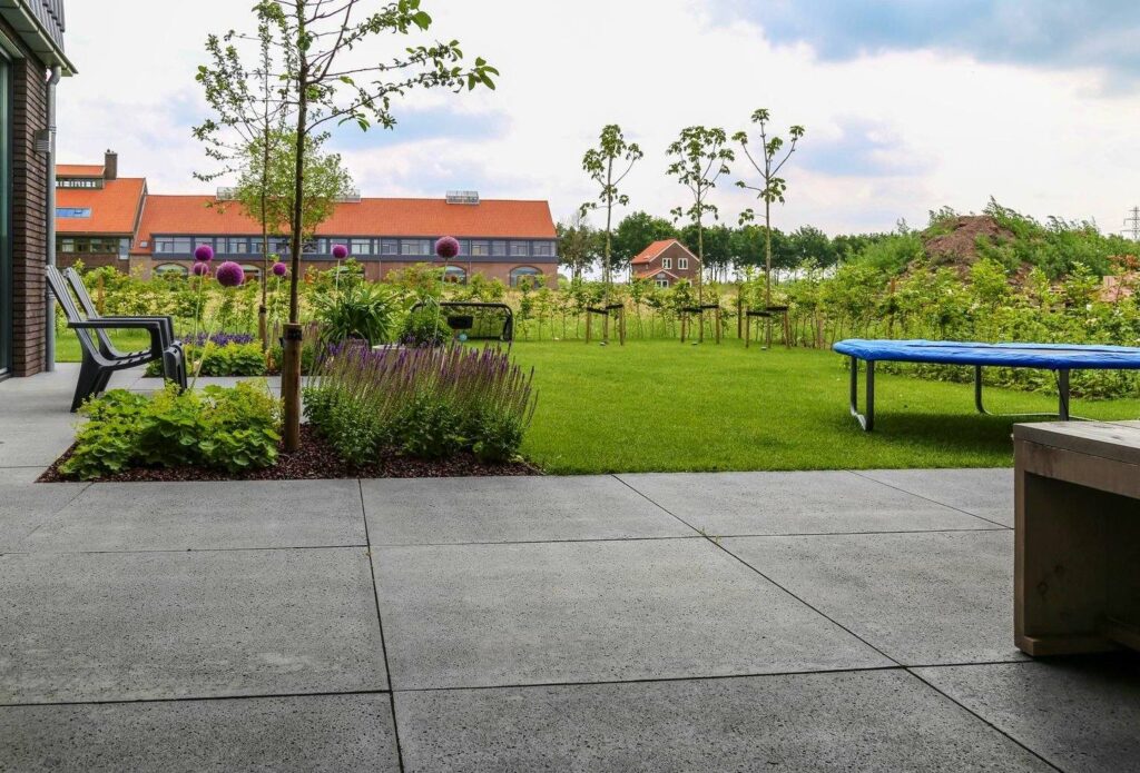 Groot terras met gazon en trampoline bij een moderne woning in Wageningen