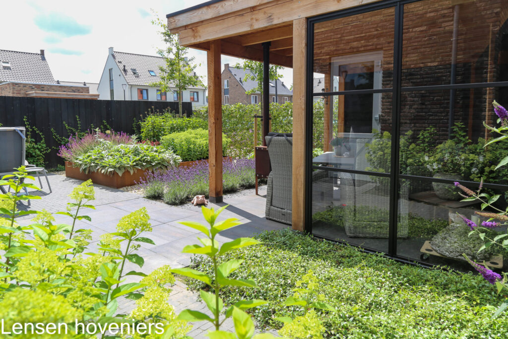 Overkapping met glazen wand tussen groene beplanting