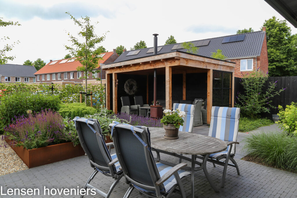 Terras met tuinstoelen voor de overkapping met houtkachel