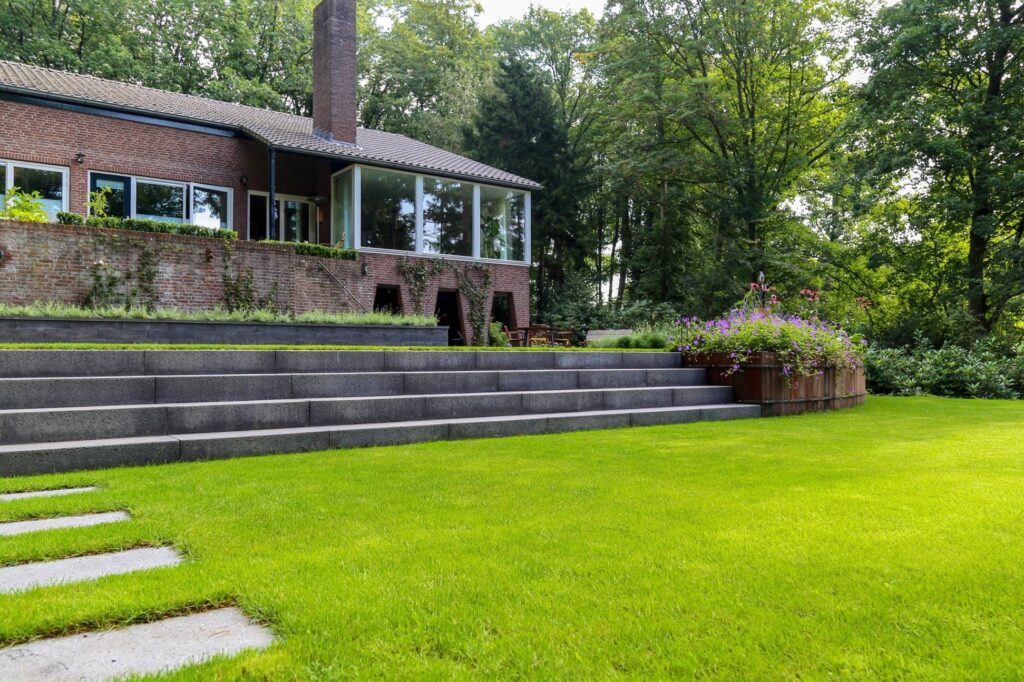 Brede trap en gazon voor een bungalow in een bosrijke tuin in Arnhem