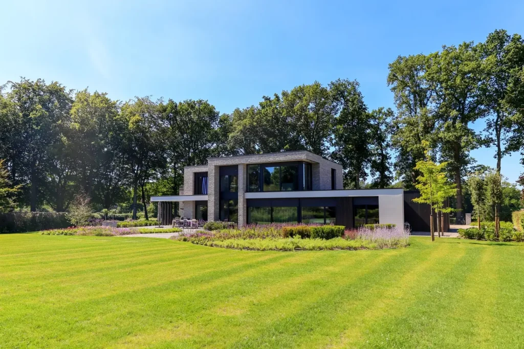 Groot gazon met maaibanen voor een villa tussen hoge bomen in Oosterbeek